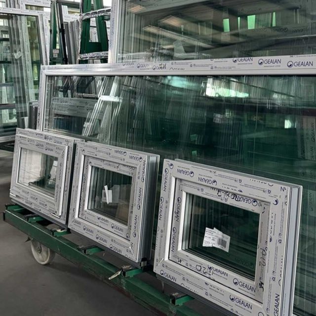 Balti PVC logu rāmji un stikla paketes ratiņos ražotnes noliktavā